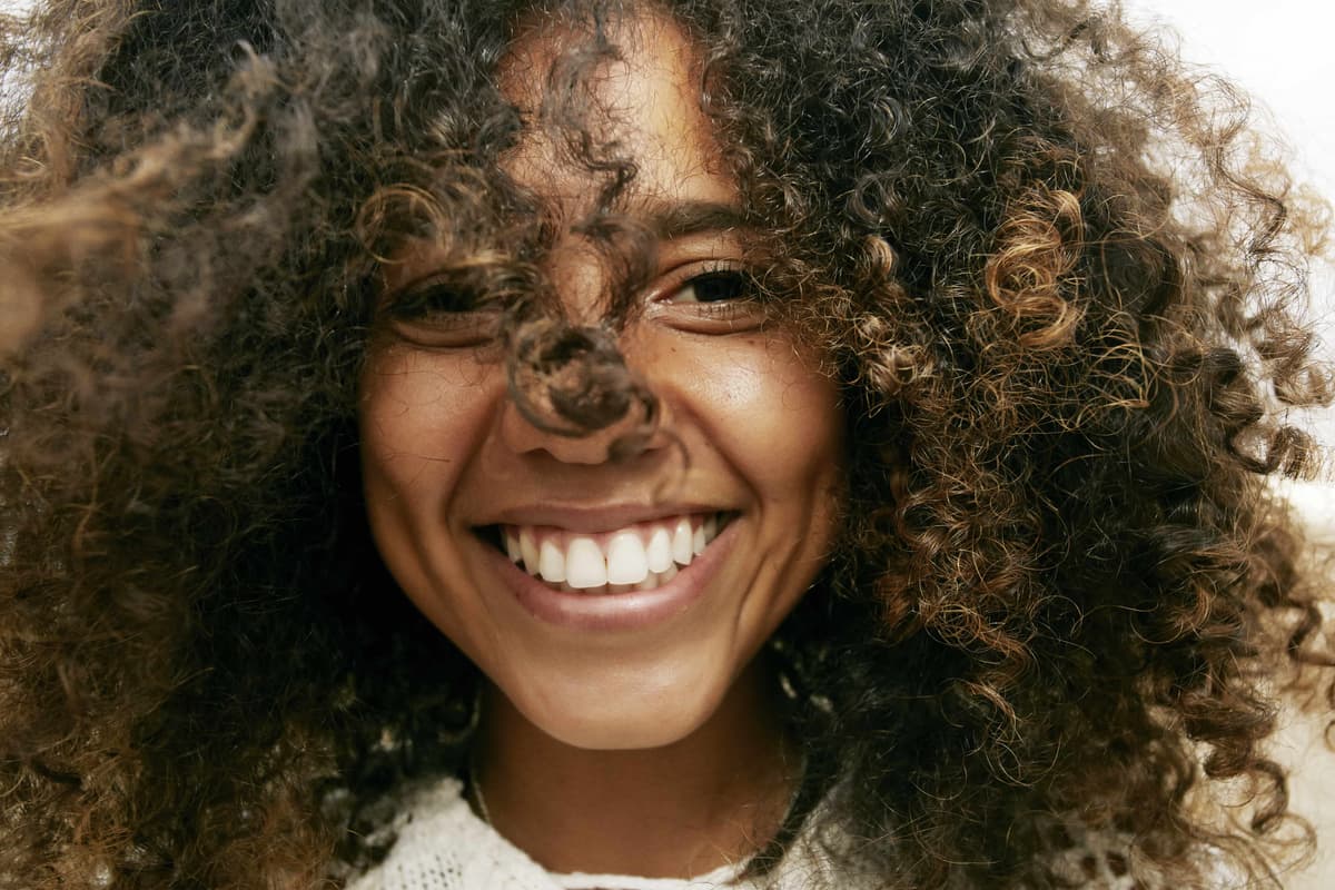 portrait-of-smiling-young-woman-with-brown-curly-h-2023-11-27-05-14-15-utc-min.jpg