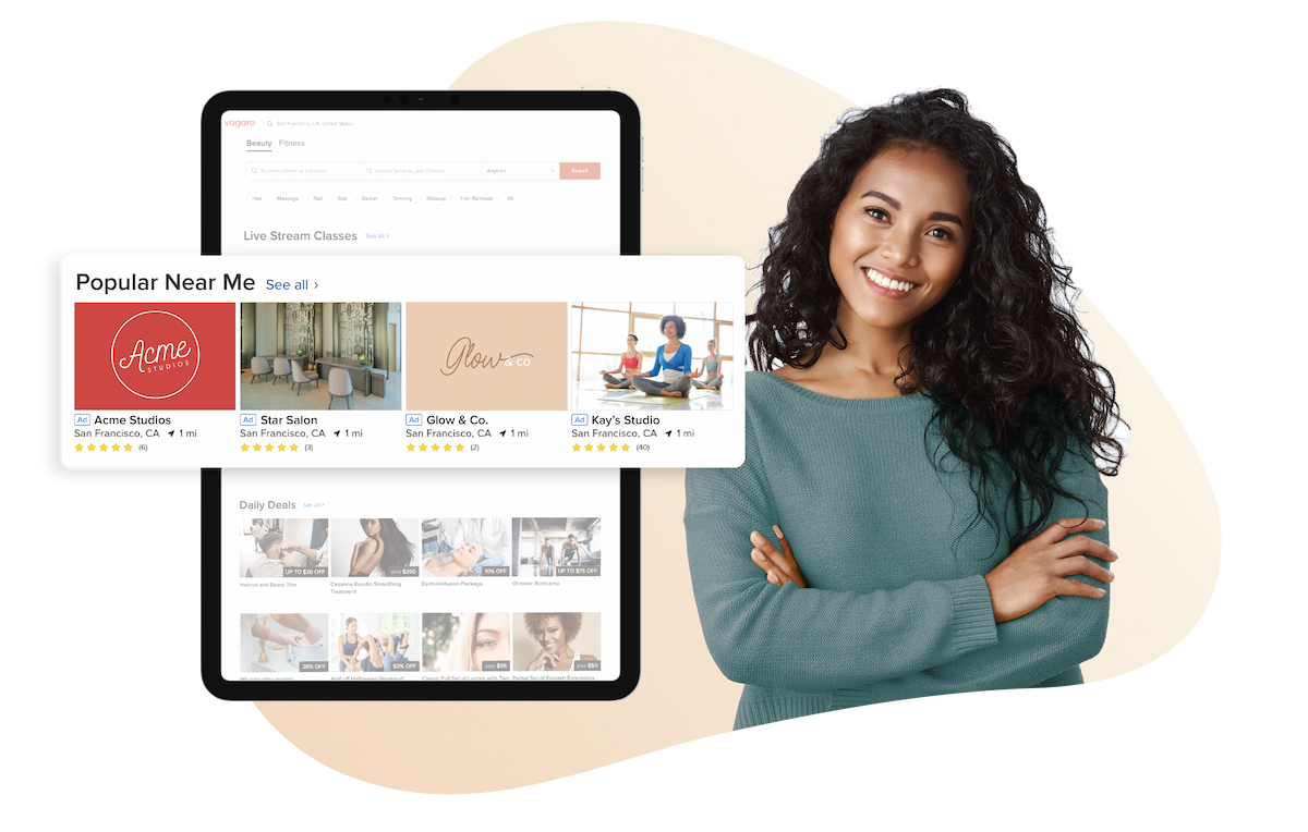 A picture of a woman stood next to a tablet that shows our Get Featured section in the Vagaro marketplace.